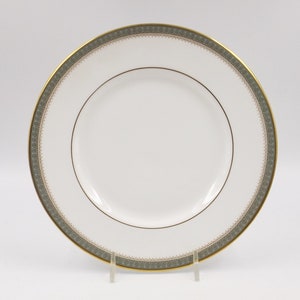 Puede incluir: Un plato de cerámica blanco con un borde verde y dorado. El plato tiene un diseño sencillo y es perfecto para servir una variedad de platos.