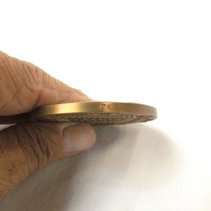 Puede incluir: Una medalla de bronce con el n&uacute;mero 0782 grabado en el borde.