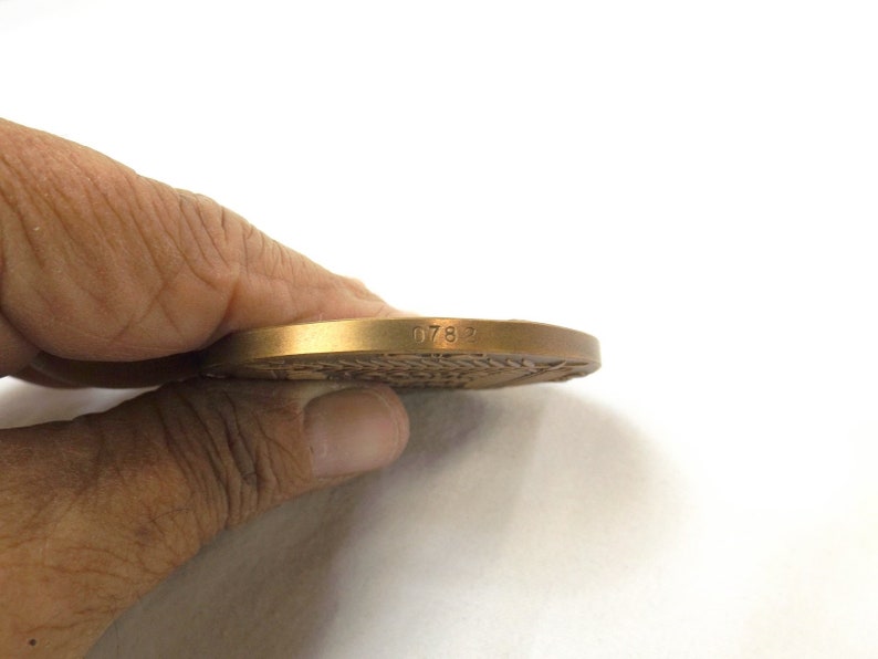 Puede incluir: Una medalla de bronce con el n&uacute;mero 0782 grabado en el borde.