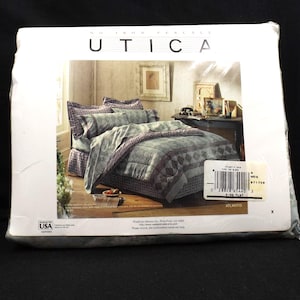 May include: A packaged King Flat bed sheet set. The bedding features a grey and purple diamond pattern. The packaging displays the brand name "UTICA" at the top. The set includes a comforter, sheets, and pillowcases.