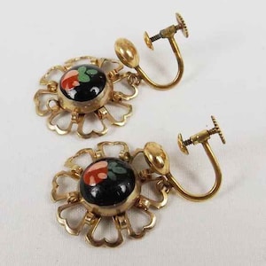 May include: A pair of gold tone clip-on earrings with black and red enamel flower designs.
