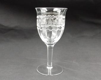 May include: A clear glass wine glass with a geometric pattern etched around the bowl.