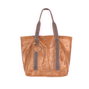 May include: A brown leather tote bag with dark brown straps and handles. The bag has a textured appearance and a small, round leather tag attached to the front. The bag is designed with a rectangular shape and is suitable for carrying various items.
