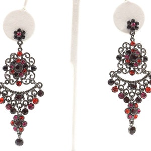 May include: A pair of dangle earrings with a black metal filigree design and red and pink crystals.