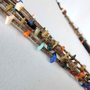May include: Multi-strand necklace with turquoise, coral, lapis lazuli, and shell beads. The necklace is made of brown leather cord and features a variety of colors and textures.
