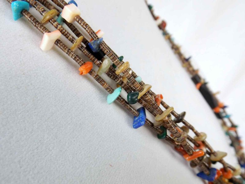 May include: Multi-strand necklace with turquoise, coral, lapis lazuli, and shell beads. The necklace is made of brown leather cord and features a variety of colors and textures.