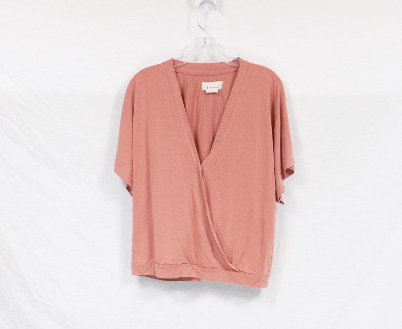 May include: A dusty rose colored short-sleeved wrap top with a V-neckline.