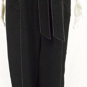 May include: Black wide-leg pants with white stitching detail. The pants have a wide waistband with a self-tie belt.