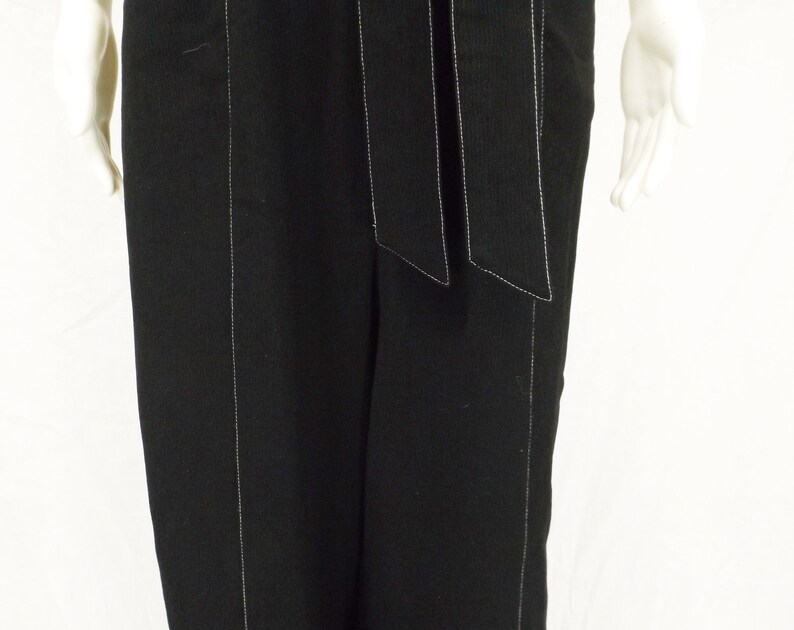 May include: Black wide-leg pants with white stitching detail. The pants have a wide waistband with a self-tie belt.