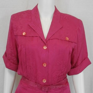 May include: A pink short-sleeved dress with a collared neckline and a button-up front. The dress has a floral pattern and a belt.