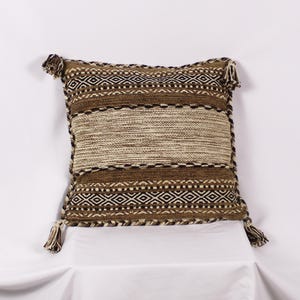 Peut inclure: Un coussin de décoration rayé brun et crème avec des motifs géométriques noirs et blancs. Le coussin a des glands à chaque coin.