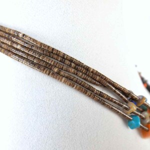 May include: A multi-strand necklace made of brown shell beads with turquoise, blue, and orange accents.