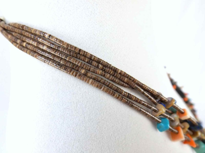 May include: A multi-strand necklace made of brown shell beads with turquoise, blue, and orange accents.