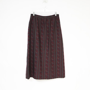 Puede incluir: Una falda larga negra con un estampado de paisley en tonos rojos y verdes.