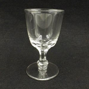 Può includere: Un bicchierino da shot in vetro trasparente con gambo. Il bicchiere ha un design semplice ed elegante.