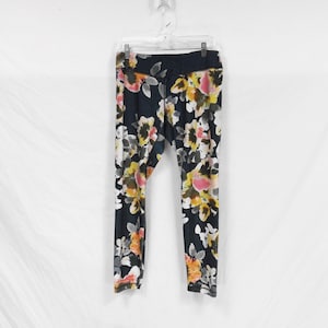 May include: Black leggings with a floral print featuring pink, yellow, and white flowers on a dark background.
