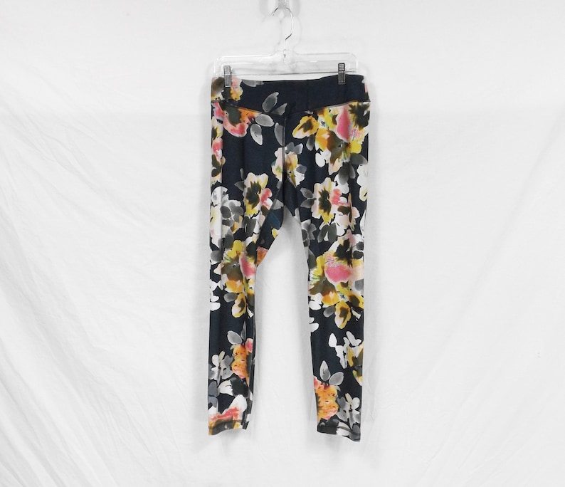 May include: Black leggings with a floral print featuring pink, yellow, and white flowers on a dark background.