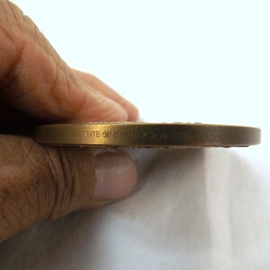 Puede incluir: Primer plano del borde de una moneda de bronce con la inscripci&oacute;n "STATE OF ISRAEL" en el lateral.