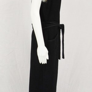May include: A black sleeveless jumpsuit with a wide belt and pockets. The jumpsuit is made of a soft, comfortable fabric and has a relaxed fit.