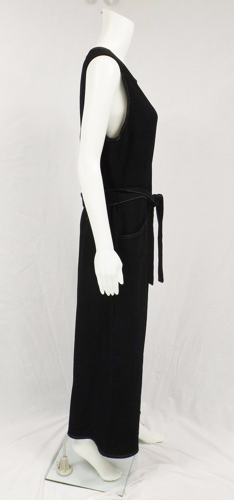 May include: A black sleeveless jumpsuit with a wide belt and pockets. The jumpsuit is made of a soft, comfortable fabric and has a relaxed fit.