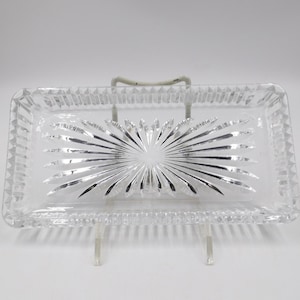 May include: A clear glass serving tray with a starburst pattern. The tray is rectangular and has a raised edge.