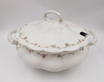 May include: White porcelain serving bowl with a lid, featuring a delicate floral pattern in shades of pink, blue, and yellow. The bowl has a scalloped edge and two handles.