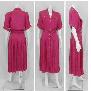 May include: A pink midi dress with a button-up front, short sleeves, and a pleated skirt. The dress has a belt and pockets.