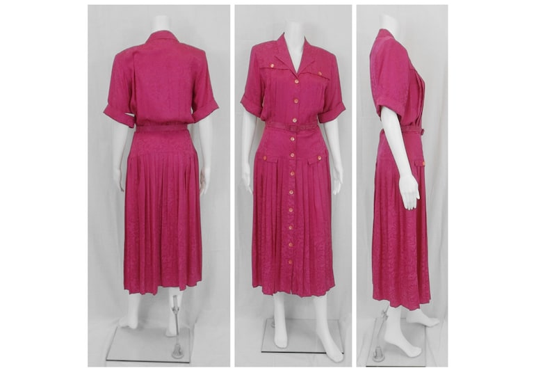 May include: A pink midi dress with a button-up front, short sleeves, and a pleated skirt. The dress has a belt and pockets.