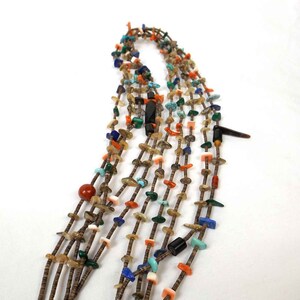 May include: Multi-strand necklace made of various stones and beads, including turquoise, coral, and shell. The necklace is brown and features a variety of colors and textures.