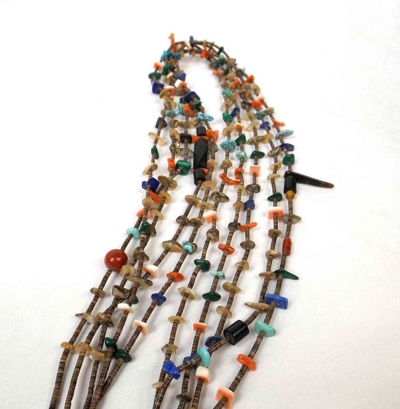 May include: Multi-strand necklace made of various stones and beads, including turquoise, coral, and shell. The necklace is brown and features a variety of colors and textures.
