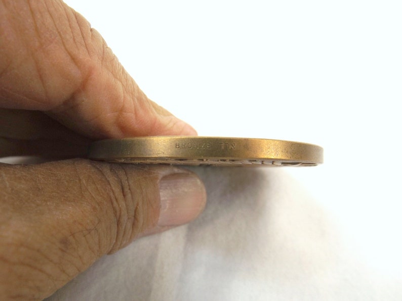 Puede incluir: Primer plano del borde de una medalla de bronce con la inscripci&oacute;n "BRONZE TIN" visible.