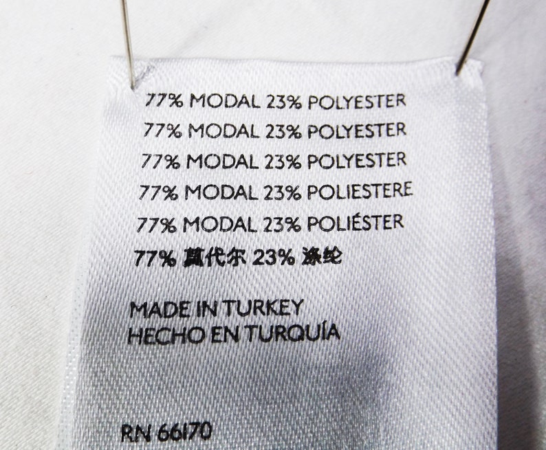 May include: White fabric label with black text. The label lists the fabric content as 77% Modal and 23% Polyester in English, Italian, Spanish, and Chinese. The label also states "Made in Turkey" and "Hecho en Turqu&iacute;a". The label includes the RN number 66170.