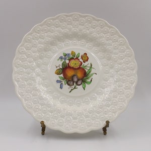 May include: White ceramic saucer with a raised, embossed design. The center features a hand-painted floral motif with red, orange, yellow, green, blue, and purple flowers and fruit.