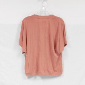 May include: A salmon-colored short-sleeved t-shirt with a round neckline.