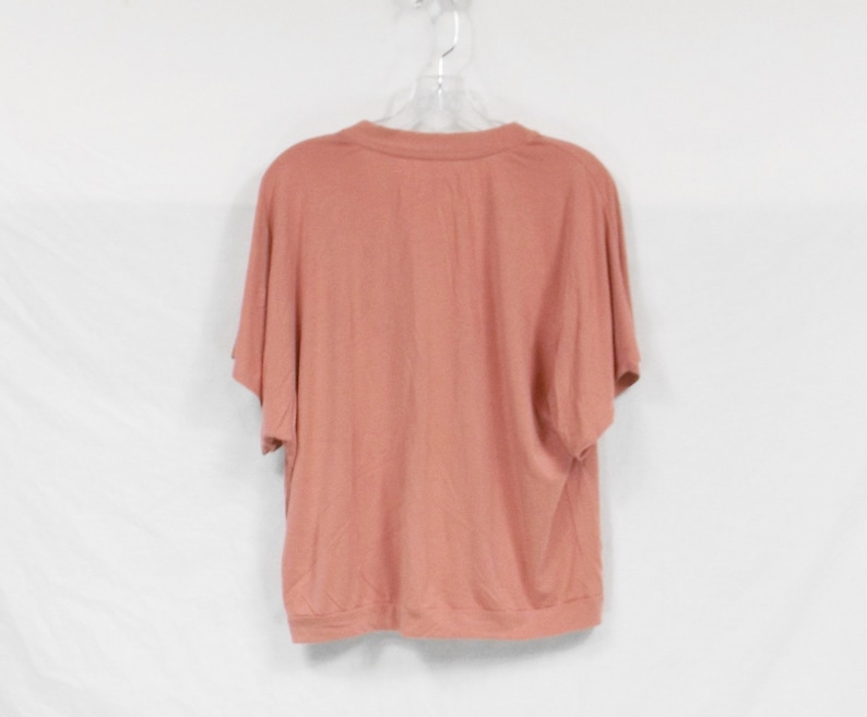 May include: A salmon-colored short-sleeved t-shirt with a round neckline.