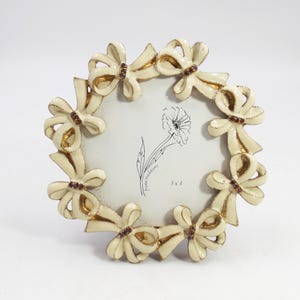 Marco de fotos redondo de 4 pulgadas con soporte de metal esmaltado y lazos enjoyados, con base de caballete.