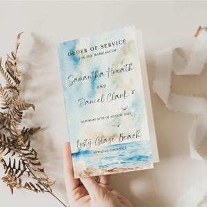 May include: A wedding order of service card with a watercolor beach scene. The card reads "Order of Service" and lists the names "Samantha Howath and Daniel Clark" with the date "Saturday 27th of August 2023" and location "Lusty Glaze Beach, Newquay, Cornwall."