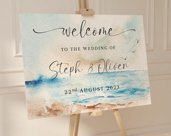 Könnte beinhalten: Ein Hochzeits-Willkommensschild auf einer Staffelei, im Aquarellstil. Auf dem Schild steht in Schreibschrift "welcome", gefolgt von "TO THE WEDDING OF Steph & Oliver 22nd AUGUST 2023" über einer Strandlandschaft.