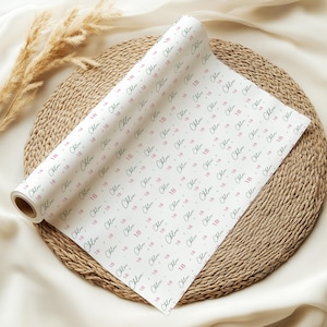 May include: A roll of white wrapping paper featuring a repeating pattern of the name Chloe in a dark green script font interspersed with the number 18 in a pink sans-serif font, arranged in diagonal rows across the surface of the paper.
