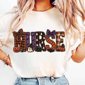 Könnte beinhalten: Ein cremefarbenes T-Shirt mit dem Wort NURSE in großen, dekorativen Buchstaben. Jeder Buchstabe hat ein einzigartiges Halloween-Muster, darunter orange-schwarze Karos, violette Fledermäuse, Geister, Sterne, Kürbisse und ein schwarzer Hexenhut.