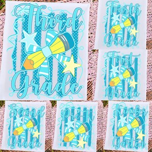 Könnte beinhalten: Ein weißes Stoffpaneel mit einem grafischen Design aus einem gelben Bleistift, einer hellblauen Schleife und gelben Sternen. Das Design enthält vertikale, blaugrüne gepunktete Streifen und Text, der verschiedene Klassenstufen angibt.