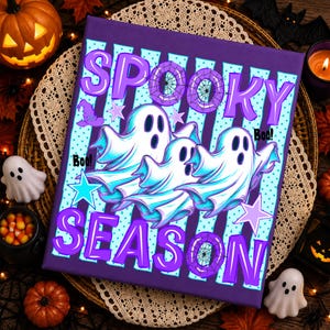 May include: A rectangular canvas print featuring a purple and light blue striped background with three white ghosts and the text SPOOKY SEASON in large purple letters. The design includes purple spider webs, stars, and a witch hat graphic.