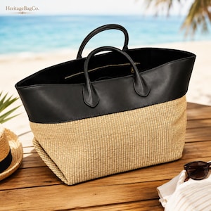 May include: A large tote bag featuring a natural woven straw base and a smooth black leather upper section with two matching black leather handles. The interior is lined in black and includes a zippered pocket. The text HeritageBagCo. is visible.