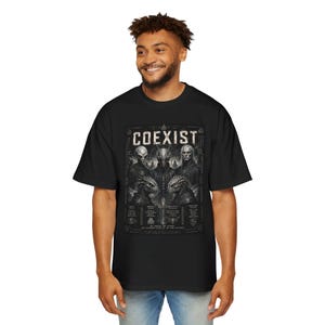 May include: A black short-sleeve t-shirt featuring a graphic print with the text COEXIST at the top. The design includes detailed illustrations of five distinct extraterrestrial and reptilian figures arranged in a grid, accompanied by small symbols and text.