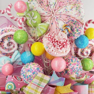 May include: A colorful, whimsical arrangement of decorative candies and sweets. The display features a large, pink and white lollipop, candy balls, and various ribbons in shades of pink, green, yellow, and blue. Sprinkles and glitter add to the festive look.