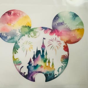 May include: A decal featuring a Mickey Mouse head silhouette filled with a watercolour rainbow pattern. Inside the silhouette is a dark blue castle graphic surrounded by stylised fireworks, all set against a plain white background.