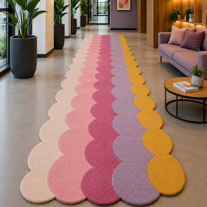 May include: A long runner rug featuring a scalloped edge design with vertical stripes in shades of light pink, medium pink, magenta, lavender, and mustard yellow. The rug has a textured, tufted surface and extends across the floor.