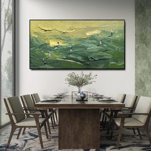 Op de afbeelding: Een olieverfschilderij dat een golfbaan met golfers afbeeldt. Het kunstwerk heeft een textuur, impasto-stijl met tinten groen en geel. Het ingelijste schilderij hangt boven een eettafel.