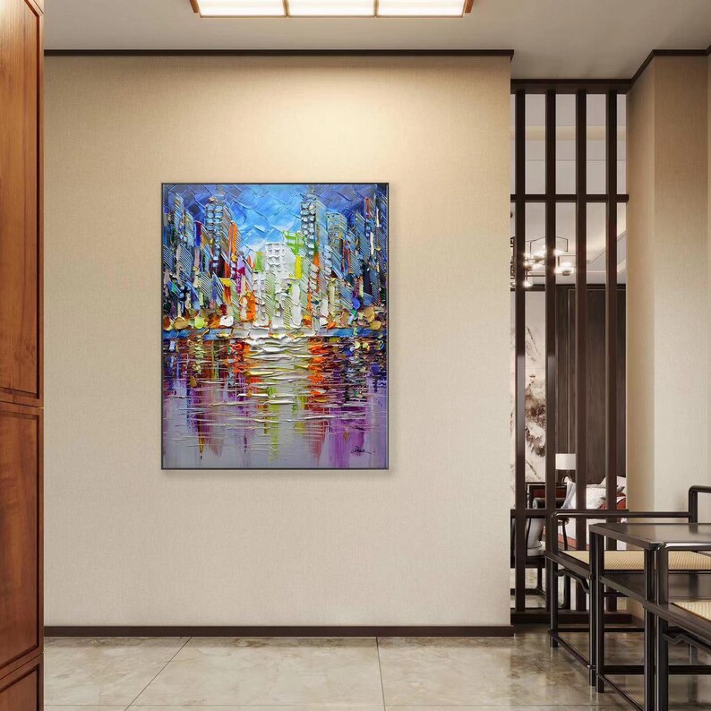 Puede incluir: Pintura abstracta de un horizonte urbano con edificios coloridos reflejados en el agua. La pintura est&aacute; realizada en un estilo grueso y texturizado con pinceladas visibles.