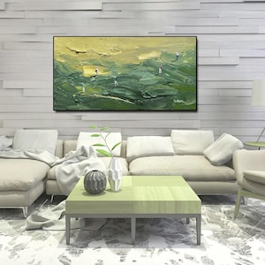Op de afbeelding: Een olieverfschilderij van een golfbaan met golfers. Het kunstwerk heeft een textuur, impasto-stijl met tinten groen en geel. Het schilderij is zwart omlijst en hangt boven een moderne woonkamer.